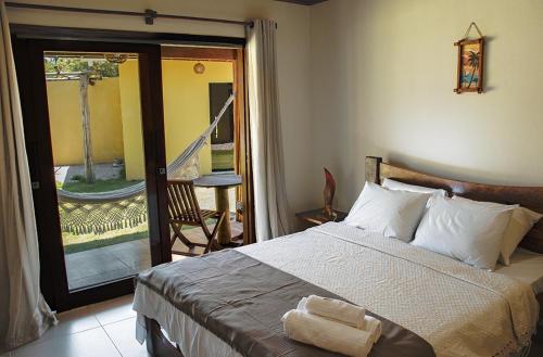um quarto com uma cama e uma porta para uma varanda em Pousada Villa Kai em São Miguel dos Milagres