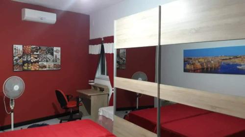 Room in Apartment - very bright well kept apartment في مارساسكالا: غرفة نوم حمراء بسرير وجدار زجاجي