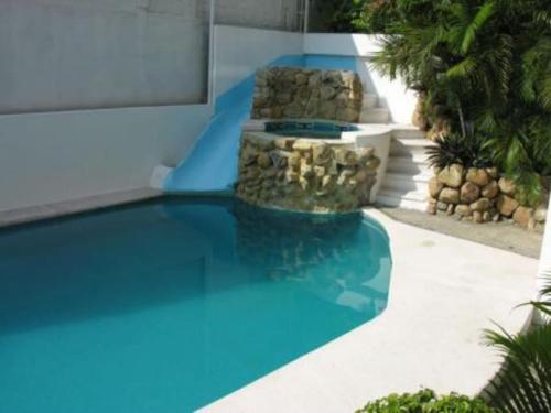 a swimming pool with a fountain in front of a building at Departamento Familiar en Acapulco con Hermosa Vista! in Acapulco