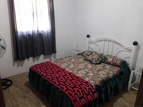 a bedroom with a bed with a red blanket and a window at Las chochitas 6p in Punta Del Diablo