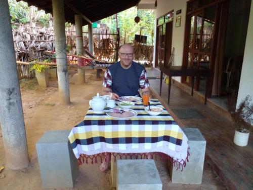 Ein Mann, der an einem Tisch mit einem Teller Essen sitzt. in der Unterkunft Ruka Homestay in Tangalle