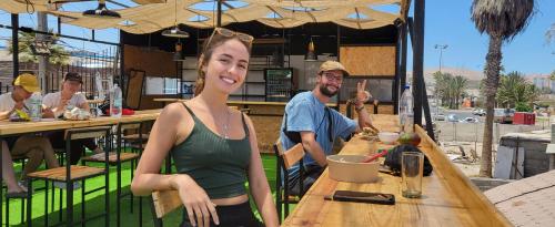 una mujer parada frente a una mesa en un restaurante en Hostel Willka Kuti Backpackers, en Arica