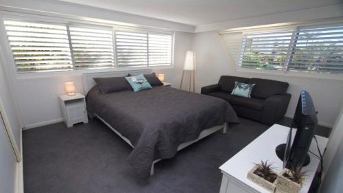 um quarto com uma cama e um sofá em Wickham Point Unit 4 Kings Beach QLD em Caloundra