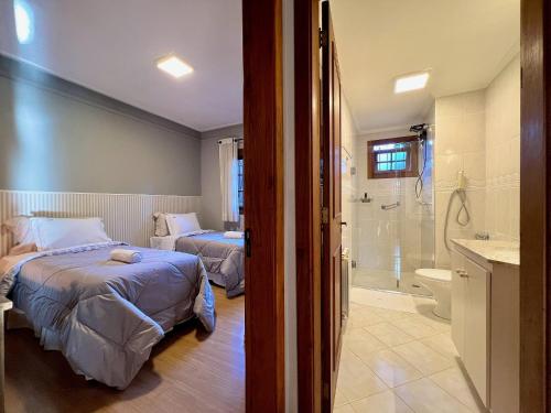 1 dormitorio con 2 camas y baño con ducha en Apartamento Dom Políbio 2 dorm by Achei Gramado, en Gramado