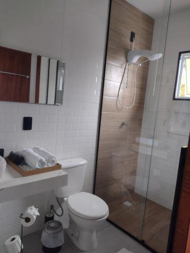 uma casa de banho com um WC e uma cabina de duche em vidro. em North Suíte em Florianópolis