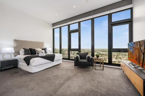 a bedroom with a bed and a tv and windows at Melbourne City Apartments Panoramic Skyview Penthouse in Melbourne