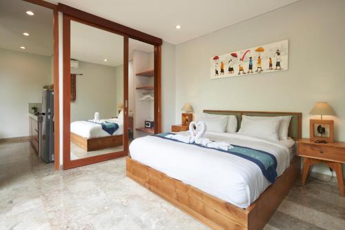 a bedroom with a large bed and a mirror at Prema Uja Villas in Ubud