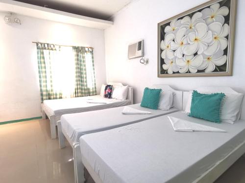 two beds in a room with a painting on the wall at La Vida Hostel Samal Island in Samal