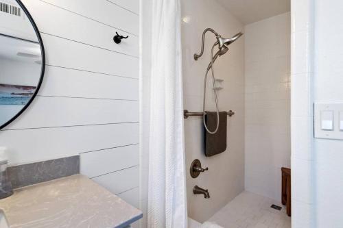 a white bathroom with a shower with a mirror at Walk on the Ocean! Wake up to Beautiful Bay Views in Newport Beach
