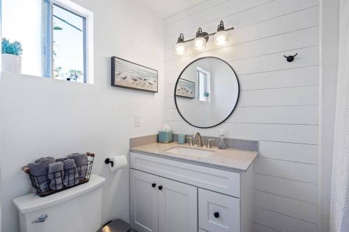 a white bathroom with a sink and a mirror at Walk on the Ocean! Wake up to Beautiful Bay Views in Newport Beach