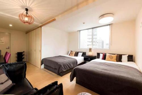 a hotel room with two beds and a couch at Hotel AIRSTAR in Fukuoka