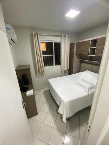 1 dormitorio con cama blanca y ventana en Apartamento vista para o mar, en Balneário Camboriú