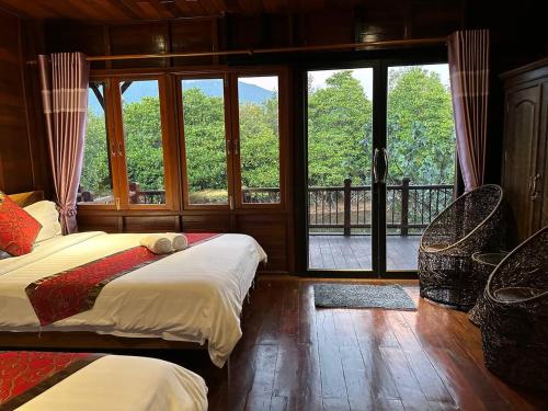 a bedroom with two beds and a balcony with windows at Prek Kdat Resort in Kampot