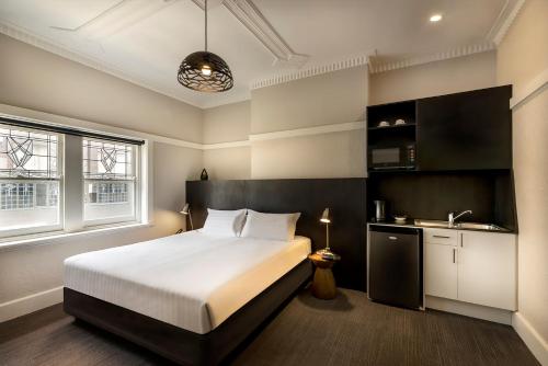 a bedroom with a large bed and a kitchen at Como Court Budget Accommodation in Melbourne