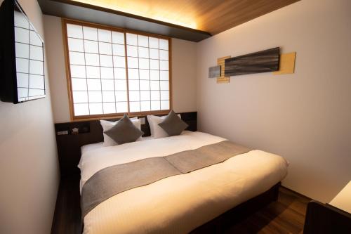 a bedroom with a large white bed with two windows at Stay SAKURA Kyoto SUZAKU OJI in Kyoto