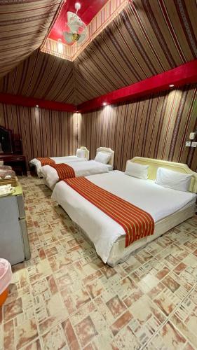 two large beds in a room with wooden walls at Bidiya Desert Camp in Aflāj