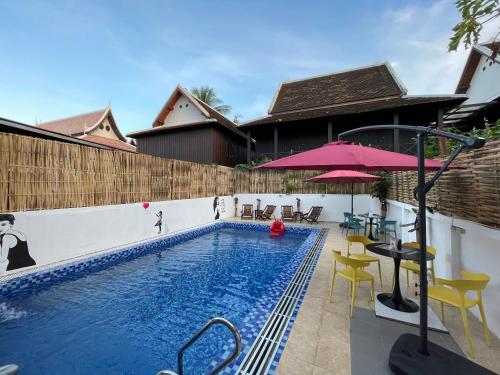 琅勃拉邦的住宿－Little Friendly Guest House and Swimming Pool，一个带椅子和粉红色遮阳伞的游泳池