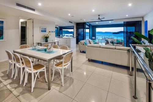 a dining room and living room with a table and chairs at Edge Apartments on Hamilton Island by HIHA in Hamilton Island
