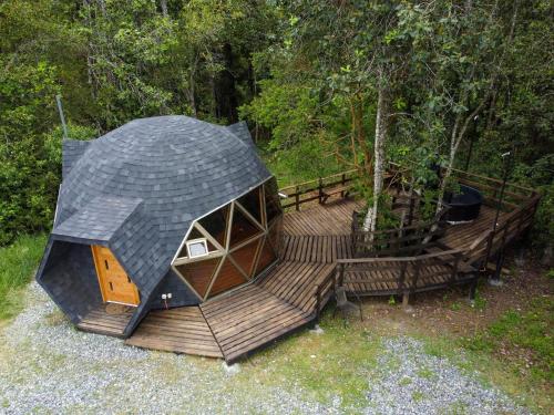 a small cabin with a wooden deck in the woods at Domos Ngen Mawida de Licanray in Licán Ray