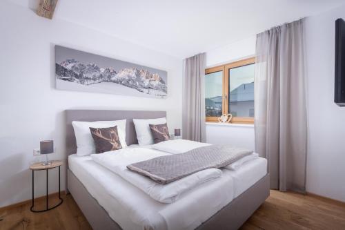 um quarto com uma cama branca e uma janela em Apartment Streif LXL em Kirchdorf in Tirol