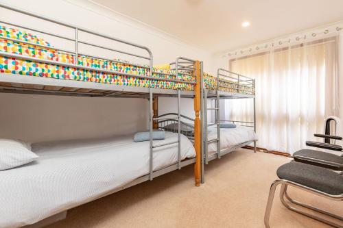 a bedroom with two bunk beds and a chair at Waterfront Haven with your own private jetty in Forster