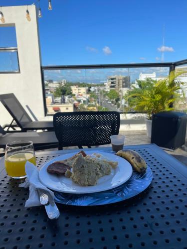 una mesa con un plato de comida y un vaso de zumo de naranja en Studio 27, en Santo Domingo