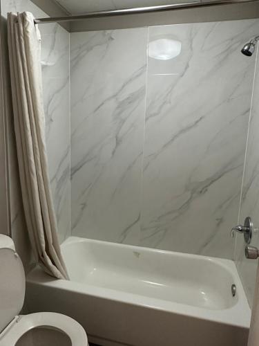een witte badkamer met een bad en een toilet bij Scottish Inn Augusta downtown in Augusta