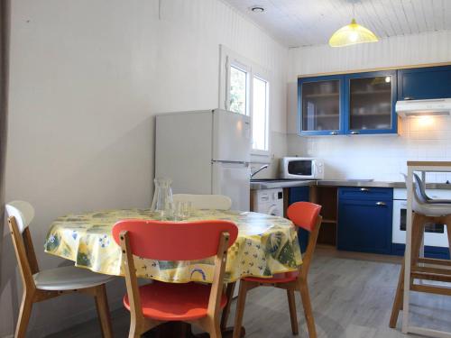 une cuisine avec une table et des chaises et une cuisine avec des armoires bleues dans l'établissement Maison 4 pers avec Terrasse et Jardin, à 2 pas du Port et de l'Océan – La Cotinière, Oléron - FR-1-246A-95, à Saint-Pierre-dʼOléron