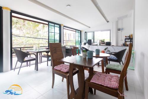 a dining room with tables and chairs and windows at Naiyang Discovery Beach Resort in Nai Yang Beach