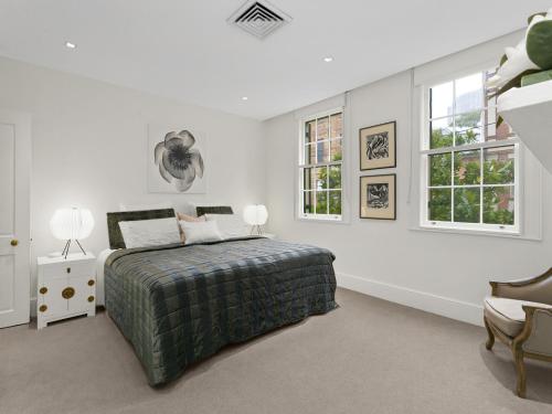 a white bedroom with a bed and two windows at WIND82D - Windmill at Dawes in Sydney