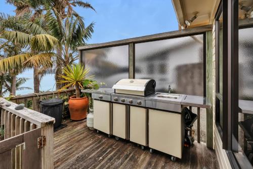 an outdoor kitchen with a grill on a deck at Coopers Sands - Coopers Beach Holiday Home in Coopers Beach