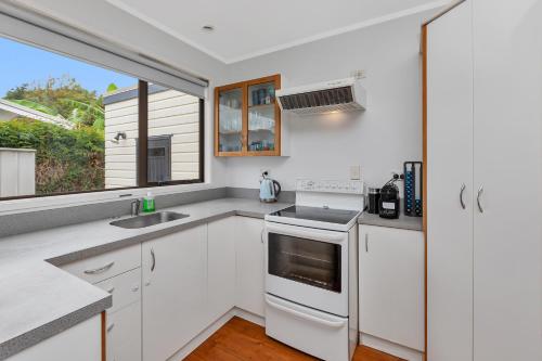 a kitchen with white cabinets and a sink and a window at Coopers Sands - Coopers Beach Holiday Home in Coopers Beach