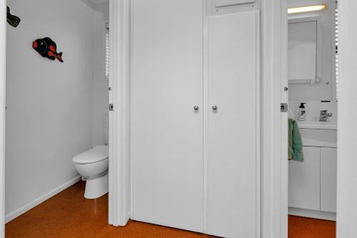 een badkamer met witte kasten en een toilet bij Coopers Sands - Coopers Beach Holiday Home in Coopers Beach