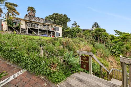 a house sitting on top of a hill with a wooden staircase at Coopers Sands - Coopers Beach Holiday Home in Coopers Beach