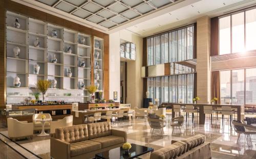 a lobby with tables and chairs and large windows at Four Seasons Hotel Tianjin in Tianjin