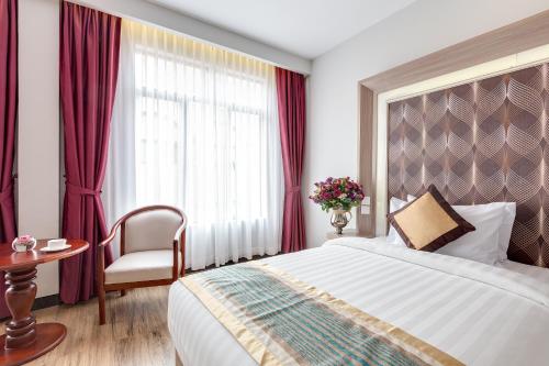 a hotel room with a bed and a chair and a window at New York Hotel in Phnom Penh