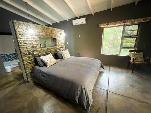 een slaapkamer met een groot bed en een stenen muur bij Ukuthula @ the Kruger in Marloth Park