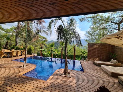 una piscina con palmeras en una terraza de madera en Metavilla en Kemer
