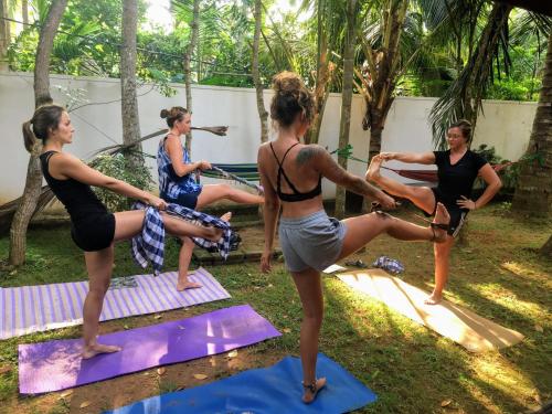 Un gruppo di donne che fanno yoga in un giardino di Hostel Singha Lounge a Unawatuna