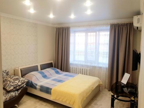 1 dormitorio con cama y ventana en квартира, en Pavlodar