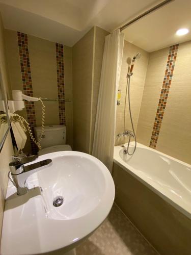 a bathroom with a white sink and a bath tub at 銀座飯店Ginza Hotel in Taipei