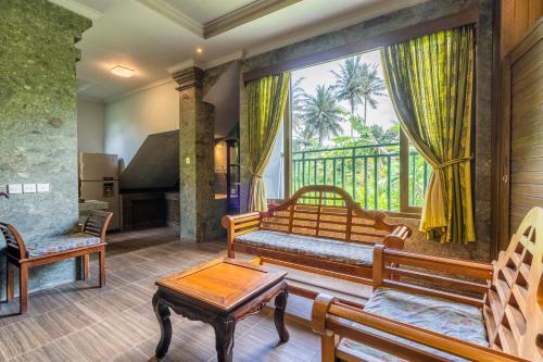 sala de estar con bancos y ventana grande en Huts Rock Ubud en Ubud