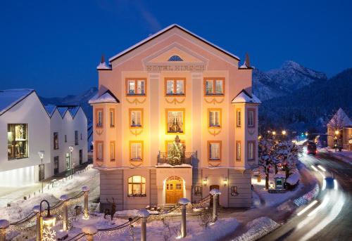 a large yellow building in the snow at night at Hotel Hirsch in Füssen
