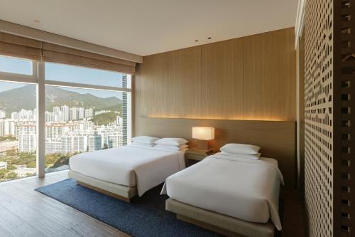 two beds in a room with a large window at Park Hyatt Busan in Busan