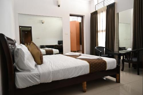 a bedroom with two beds and a desk in a room at Advaitha Serenity Resorts in Kālvādi