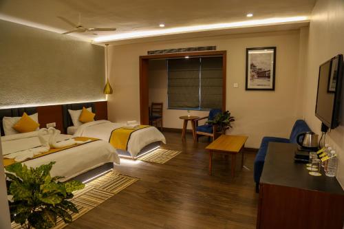 a hotel room with two beds and a table at Four Leaf Hotel - Sapphire Blue, Varanasi in Varanasi
