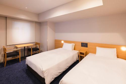 Habitación de hotel con 2 camas y escritorio en Sotetsu Fresa Inn Sapporo-Susukino, en Sapporo