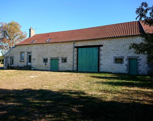 un antiguo edificio de ladrillo con puertas verdes y un patio en La fermette des Étangs, en Crux-la-Ville