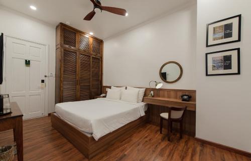 a bedroom with a bed and a desk with a mirror at Le Soleil Boutique Hotel in Da Lat