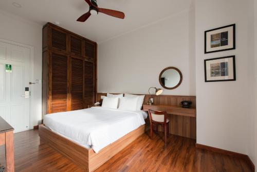 a bedroom with a bed and a table and a mirror at Le Soleil Boutique Hotel in Da Lat